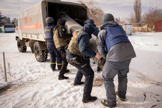 Сотрудники украинских экстренных служб грузят обломки российской ракеты С-300 в служебную машину в Харькове