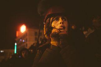 Протестующая наблюдает за столкновением между сторонниками «Евромайдана» и милицией. 11 декабря 2013 года.