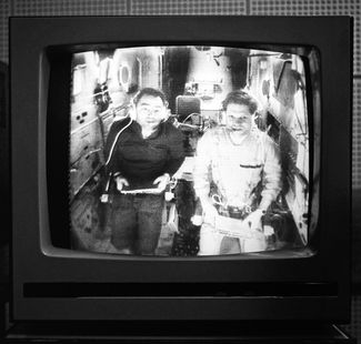Командир экипажа «Союз-17» Алексей Губарев и бортинженер Георгий Гречко (слева) по видеосвязи с борта орбитальной станции «Салют-4». На втором плане видно кресло, предназначенное для вестибулярных проб, за ним — астропост. 16 января 1975 года