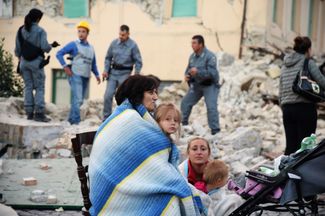 Пострадавшие при землетрясении у развалин дома