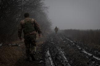 Украинские военные из артиллерийского подразделения занимают боевую позицию на покрытой грязью дороге. 4 января 2024 года