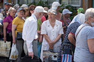 Пожилые жители Киева стоят в очереди за едой, которую раздают волонтеры