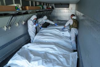 Специалисты из Международного комитета Красного Креста осматривают тела погибших российских военных, прежде чем Украина передаст их России