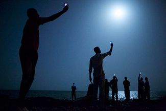Африканские мигранты на берегу Джибути Сити пытаются поймать сигнал из соседней Сомали. Фотография-победитель World Press Photo 2014