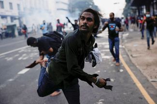 Протестующий в Коломбо бросает гранату со слезоточивым газом обратно в полицию<br>