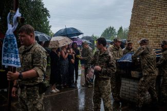 Члены семьи погибшего военнослужащего Антона Савицкого получают от военных флаг Украины. Церемония прощания состоялась на кладбище в Буче, неподалеку от Киева