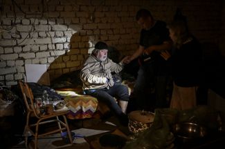 Мужчина помогает отцу в подвале их дома в Лисичанске. В городе нет электричества и воды