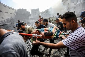 Жители Газы несут женщину, пострадавшую в результате обстрела. 12 октября 2023 года