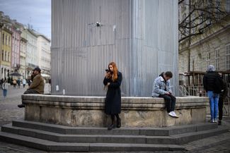 Девушка у памятника во Львове, укрытого защитным корпусом от бомбежек<br>