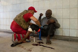 Медицинский работник помогает раненому после обстрела рынка Барабашово