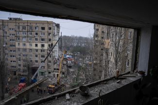 Спасатели разбирают завалы в здании, пострадавшем в результате обстрела 14 января. 