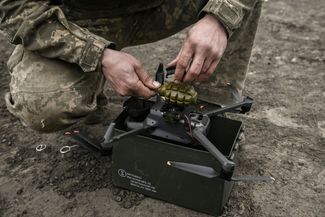 Украинский военный прикрепляет гранату к дрону перед запуском