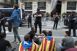 Участники демонстрации на проезжей части у здания национальной полиции в центре Барселоны