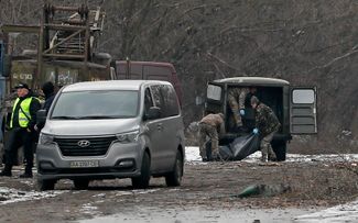 Киевские спасатели переносят тело одного из погибших во время российского обстрела