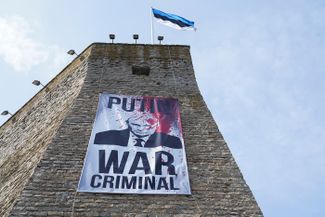 A poster reading “Putin is a war criminal” was hung on the wall of Narva Castle on the border with Russia.