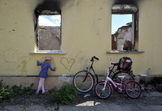 Девочка рисует на стене разрушенного дома в Андреевке под Киевом