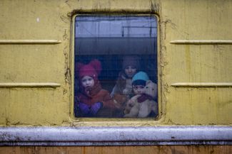 Влада, Катрин и Данила выглядывают из окна неотапливаемого вагона эвакуационного поезда, следующего во Львов. Киев, 3 марта 2022 года