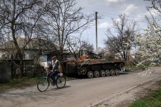 Велосипедист едет мимо остатков военной техники в селе Русанов. В Киевской области шли активные бои, и Русанов был одним из населенных пунктов, пострадавших от обстрелов