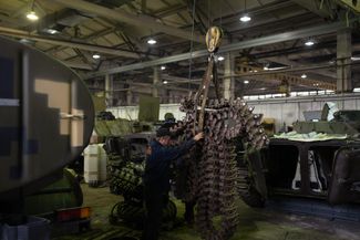 Танковый цех в Киевской области. Механики перемещают цепную гусеницу военной машины 