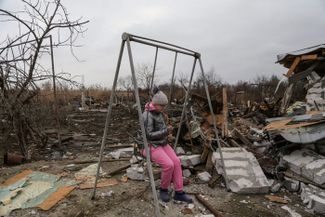 Девочка качается на качелях рядом с разрушенными домами. Одесса, 1 января 2024 года 