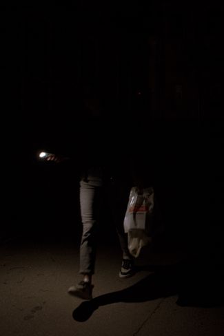Прохожий освещает себе дорогу фонариком: во время отключения электричества на улицах нет света