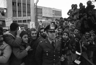 Армейский офицер с фотографией аятоллы Хомейни на фуражке перед зданием посольства США в Тегеране. 15 декабря 1979 года