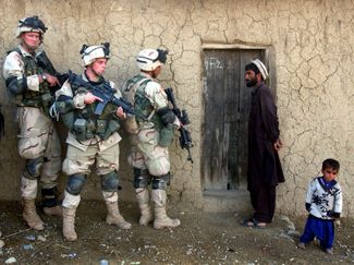 Афганец и его сын наблюдают, как бойцы 82-й воздушно-десантной дивизии армии США готовятся к обыску их дома в юго-восточном Афганистане. Во время обыска было обнаружено более десятка мин и гранат, 14 зарядов для гранатомета, а также пластиковая взрывчатка. 7 ноября 2002 года