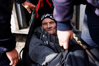 Сотрудники ГСЧС несут 74-летнего жителя Часова Яра Валерия Золотова к эвакуационному транспорту