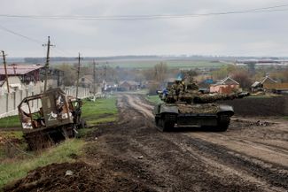 Украинский танк проходит мимо уничтоженной российской техники со знаком  «Z» в селе Гусаровка, Харьковская область