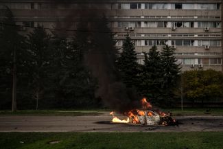 Горящая машина, уничтоженная в результате российского обстрела Харькова. В ней оставались два пассажира.