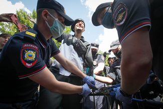 Police attempt to cut handcuffs off of activist Pavel Kristevich, who had chained himself to a fence outside the courthouse in St. Petersburg on June 22, 2020