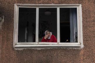 67-летняя жительница Мирнограда Елена плачет в окне своей квартиры