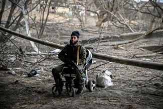 Украинский военнослужащий отдыхает в брошенной детской коляске под разрушенным мостом в Ирпене