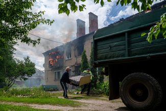 Местные жители выносят вещи из своего дома после российского авиаудара по Волчанску