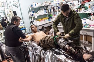 Украинские врачи готовят раненого бойца к операции