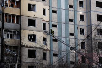 Украинские пожарные и спасатели у попавшего под обстрел многоквартирного дома в Киеве 