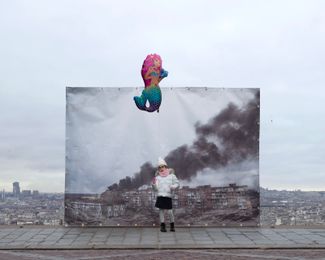 Семилетняя Кристина на фоне фотографии с видом на разбомбленный Мариуполь, которую сделал Евгений Малолетка. Кадр можно было увидеть на Монмартре в Париже