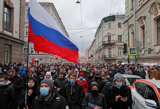 A protester carrying a Russian flag marching in a crowd in the city center
