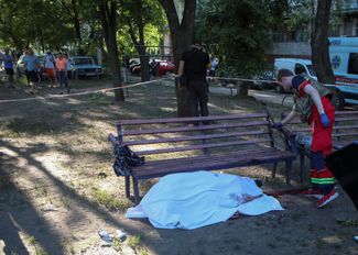 Медицинский работник рядом с телом погибшего во дворе жилого дома в Харькове.