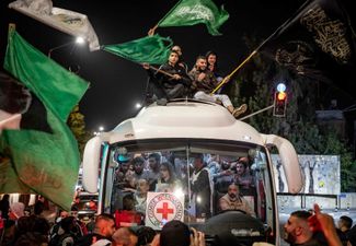 Топла палестинцев приветствует автобус Красного Креста, в котором везут заключенных, освобожденных из израильских тюрем, 26 ноября 2023 года