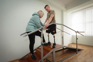 27-летний служащий ВСУ Дмитрий при помощи медсестры учится справляться со своими новыми бионическими протезами: на фронте он лишился обеих ног