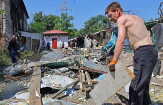 Житель Донецка помогает разбирать завалы после украинского артобстрела