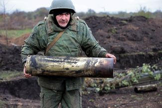 Российский военный на позиции в Донецкой области (на территории самопровозглашенной ДНР) несет, скорее всего, использованный артиллерийский снаряд для крупнокалиберной пушки-гаубицы «Гиацинт-Б»