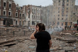 Харьковчанка на фоне одного из разрушенных ударом зданий в центре города