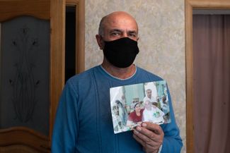 Magomed Omarov, the husband of X-ray technician Aminat Medzhidova, holds up a photo of the pair together. Medzhidova died of COVID-19 on May 2. Gergebil, Dagestan; May 27, 2020