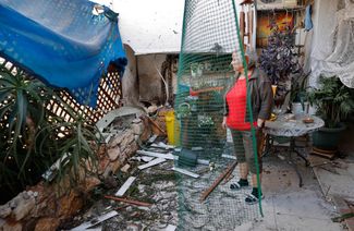 Израильтянка изучает ущерб, нанесенный ее дому после палестинского ракетного обстрела города Ашкелон. 14 мая 2021 года