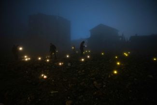 Люди зажигают свечи на развалинах разрушенного землетрясением дома, чтобы почтить память погибших близких. Город Антакья