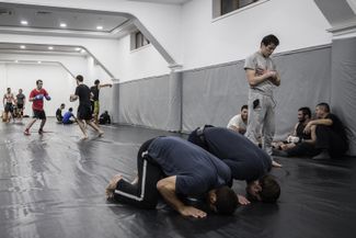 Вечерняя молитва в бойцовском клубе, которым руководит Абдулманап Нурмагомедов (крайний справа). Абдулманап — отец и тренер Хабиба Нурмагомедова, который должен был в начале марта провести статусный бой с американцем Тони Фергюсоном, но <a href="https://meduza.io/news/2017/03/04/rossiyskiy-boets-mma-otmenil-boy-za-chempionskiy-titul-habib-nurmagomedov-popal-v-bolnitsu-posle-sgonki-vesa" target="_blank">не смог этого сделать</a> из-за ухудшения здоровья во время сгонки веса.<br>