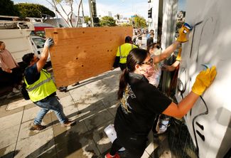 В Санта-Монике, Калифорния, убирают граффити, нанесенные участниками беспорядков. 1 июня 2020 года