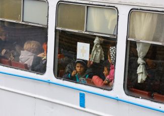 People evacuated from the city of Kherson arrive by a bus on a ferry in the city of Oleshky, in the Kherson region, October 22, 2022
